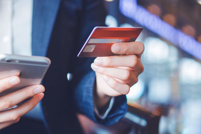 Eine Person gibt eine Kreditkartennummer in ein Smartphone ein